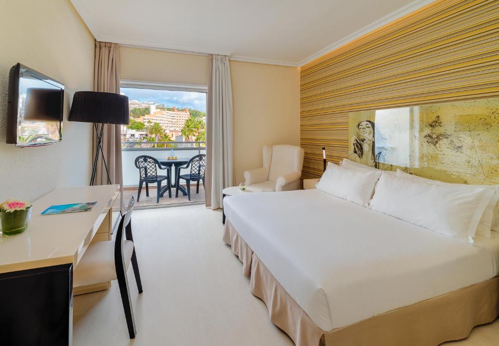 a hotel room with a bed and a desk and a window at H10 Gran Tinerfe - Adults Only in Adeje