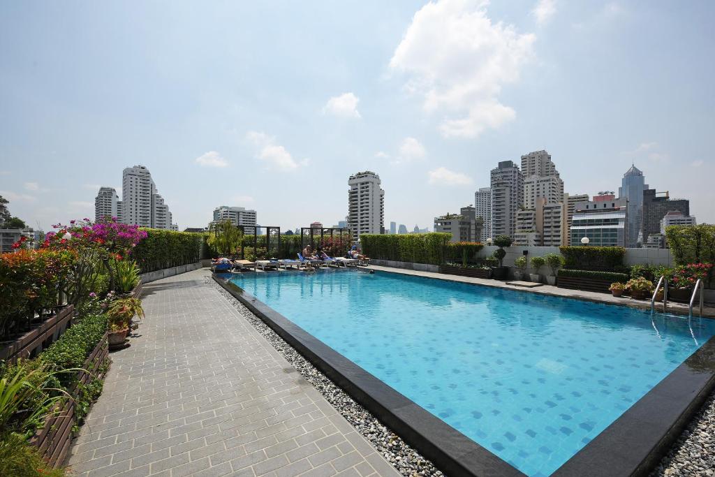 a large swimming pool with a city skyline in the background at Ruamchitt Plaza Hotel in Bangkok