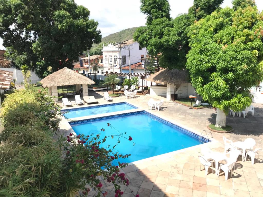 a swimming pool in a resort with chairs and trees at Pousada Convento do Carmo in Cachoeira