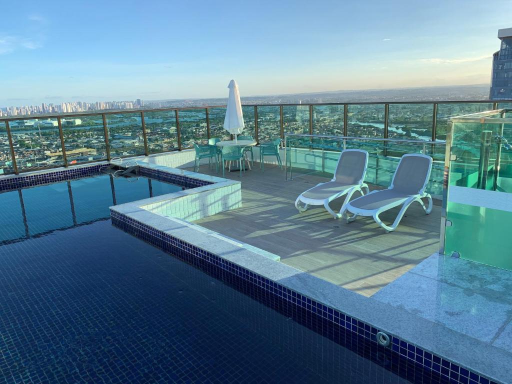 una piscina con sillas y una mesa en un edificio en Beach Class Ilha do Leite, en Recife