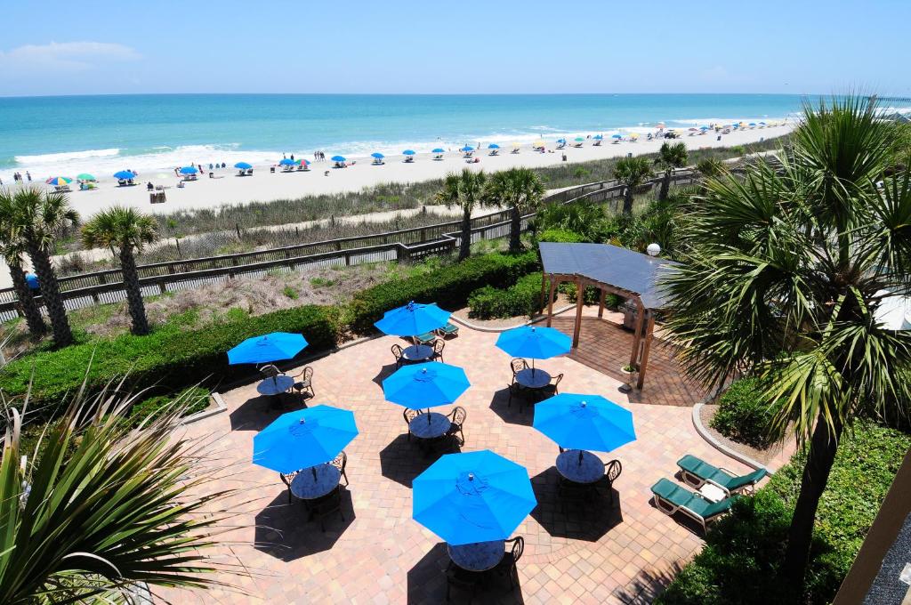an overhead view of a patio with blue umbrellas and the beach at Holiday Pavilion Resort on the Boardwalk in Myrtle Beach