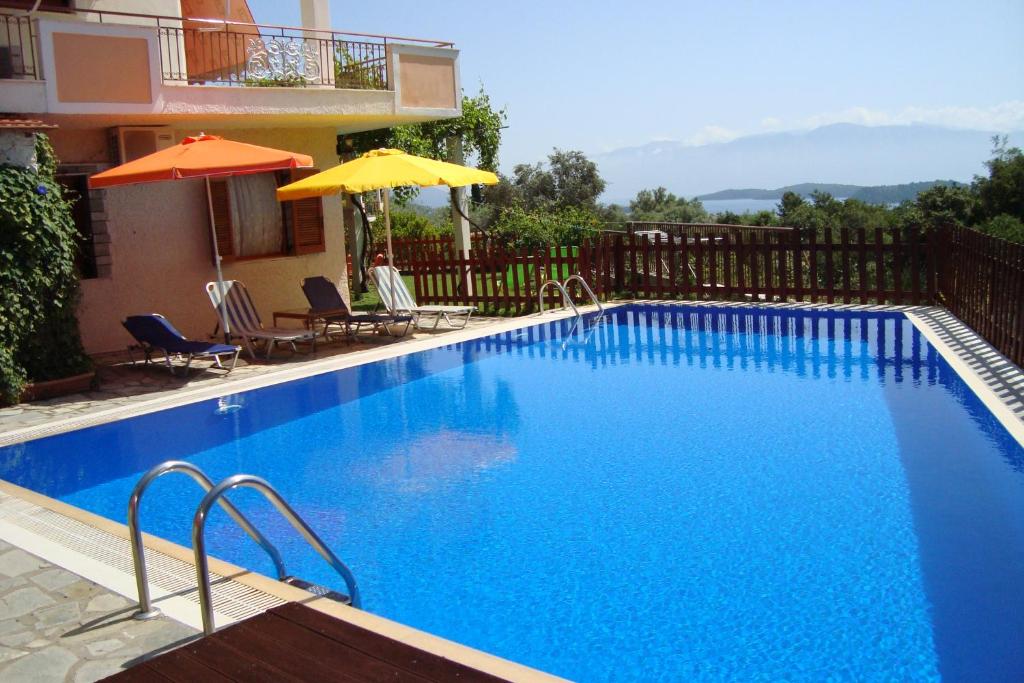 a large blue swimming pool next to a house at Villa's ground floor apartment with 60 qm swimming pool in Palaiokatoúna