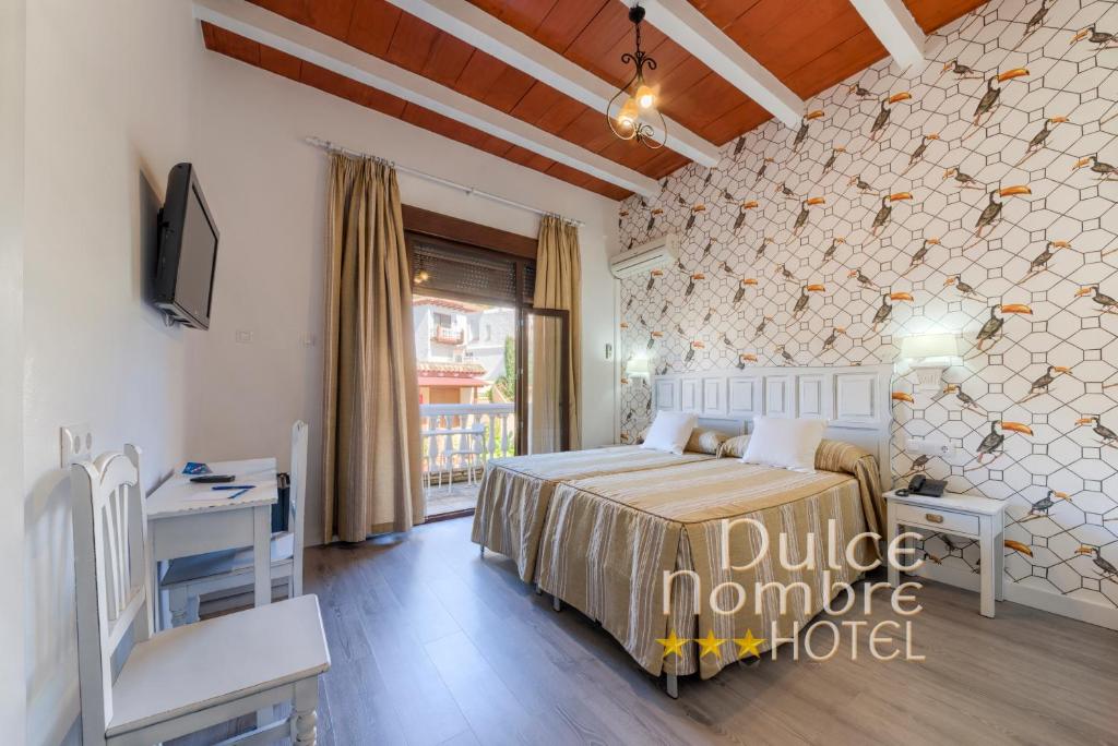 a bedroom with a bed and a desk and a tv at Dulce Nombre Hotel - Apartamentos in Tarifa