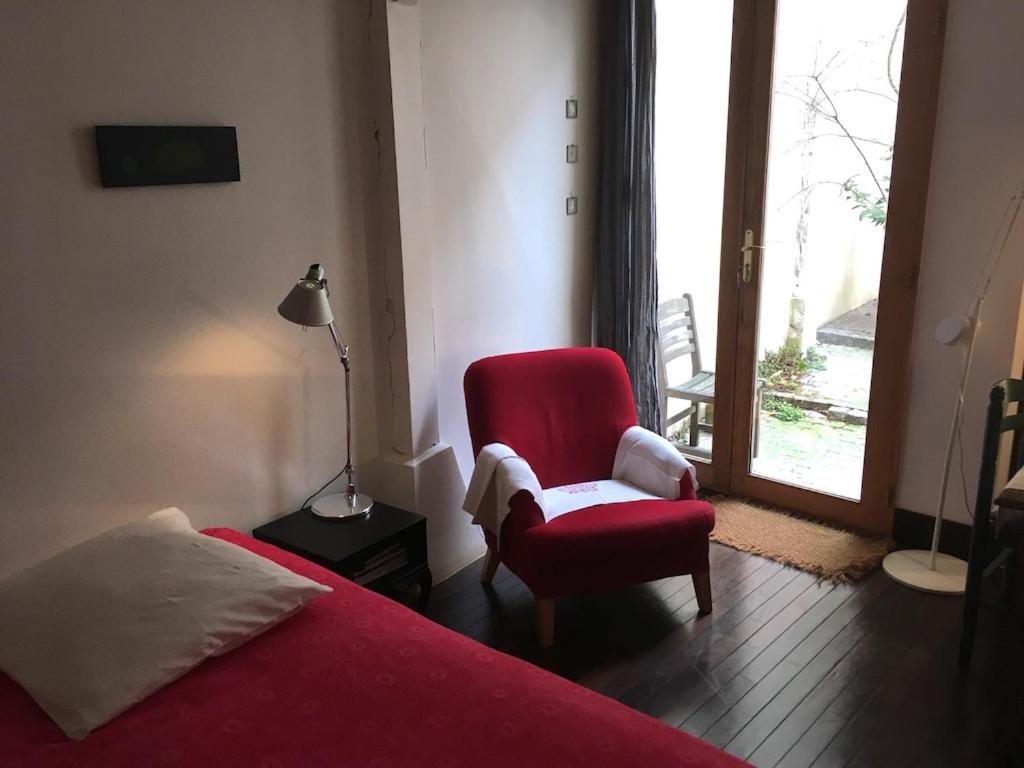 a bedroom with a red bed and a chair and a window at Chambre d'Hôtes Annelets in Paris