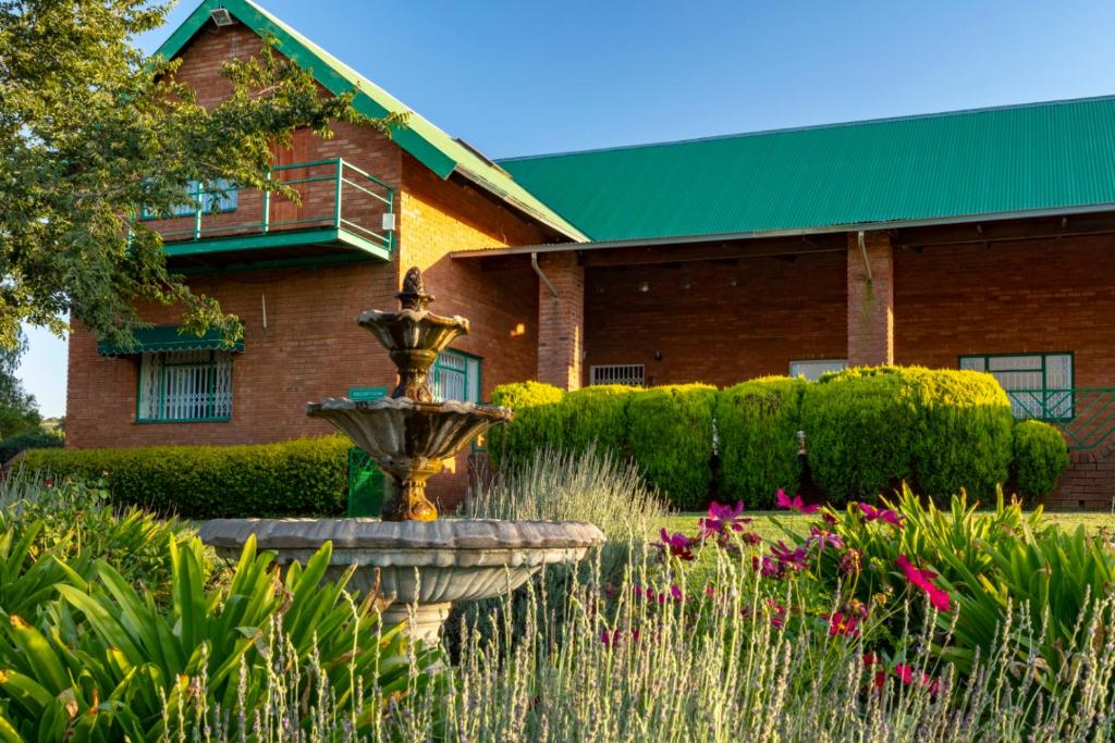 una casa con una fuente frente a un edificio en Olive Tree Farm, en Magaliesburg