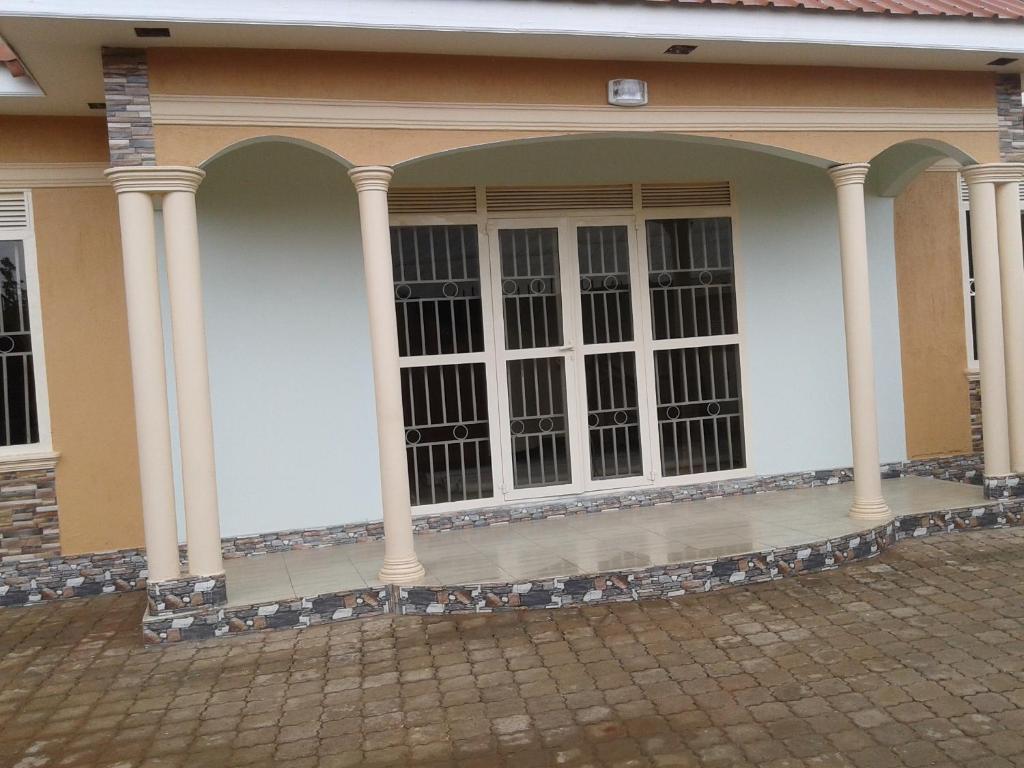ein Haus mit Säulen und Fenstern auf einer Straße in der Unterkunft FREEDOM Guest House in Wakiso
