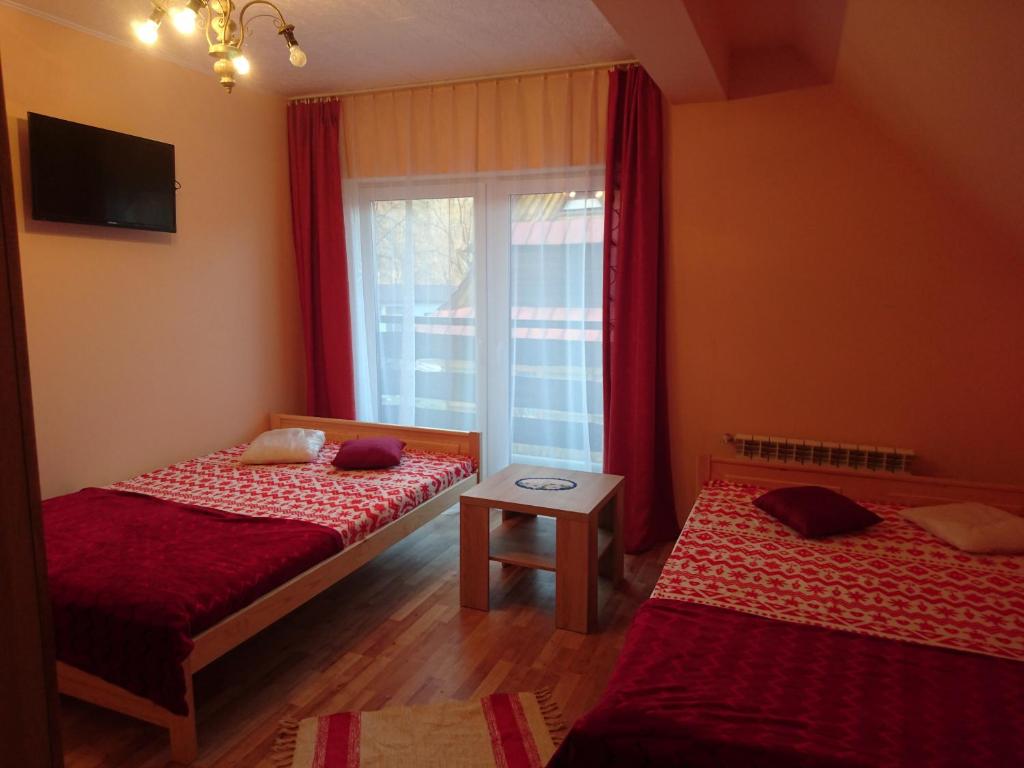 ザコパネにあるU Kasprówのベッドルーム1室(ベッド2台付)、赤いカーテン付きの窓が備わります。
