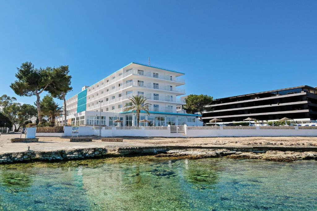 een groot wit gebouw naast een waterlichaam bij azuLine Hoteles Mar Amantis & II in San Antonio Bay