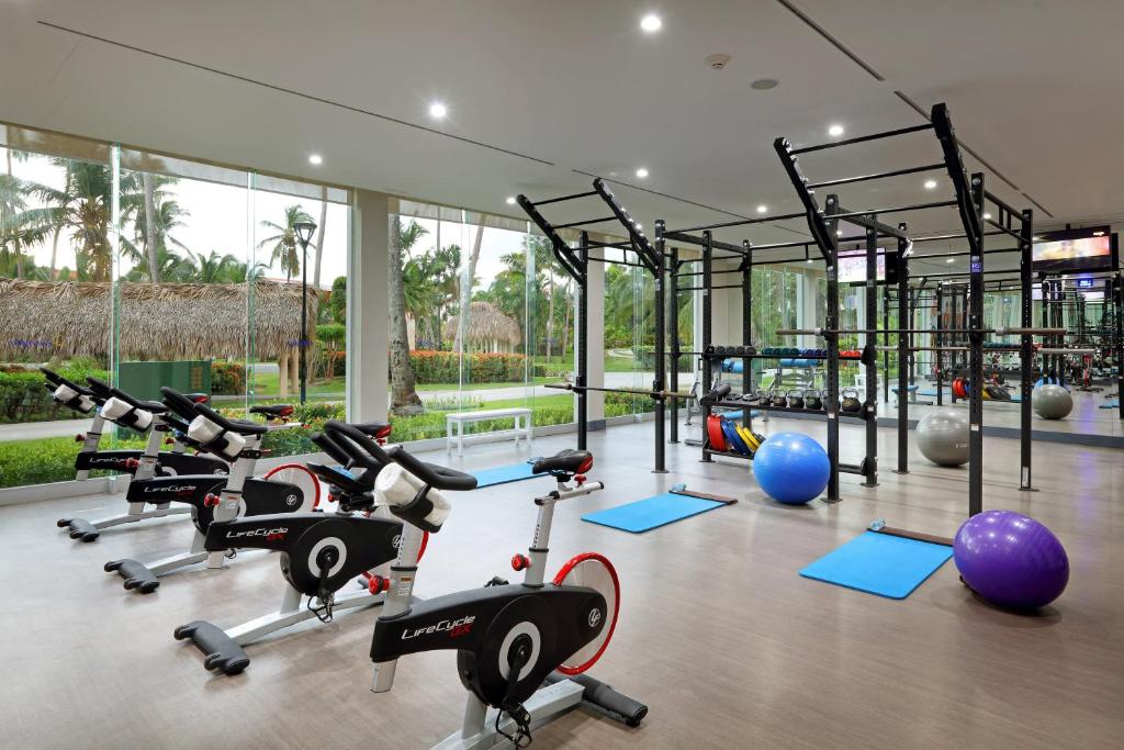 Modern fitness center with exercise bikes, dumbbells, resistance equipment, and large windows.