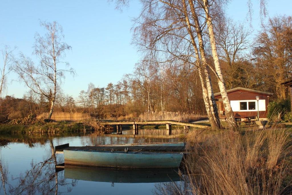 Diepenbeek的住宿－My Secret Garden，坐在房子旁边的水中的小船