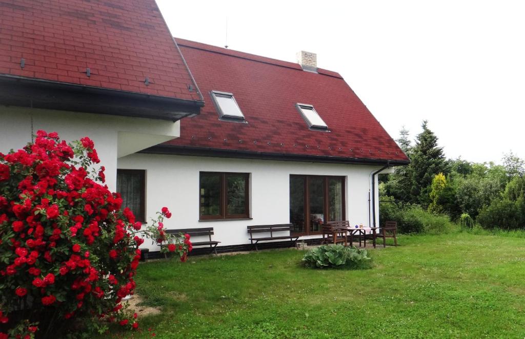 uma casa branca com um telhado vermelho e um arbusto com flores vermelhas em Prázdninový dům - PACL Červená Řečice em Červená Řečice