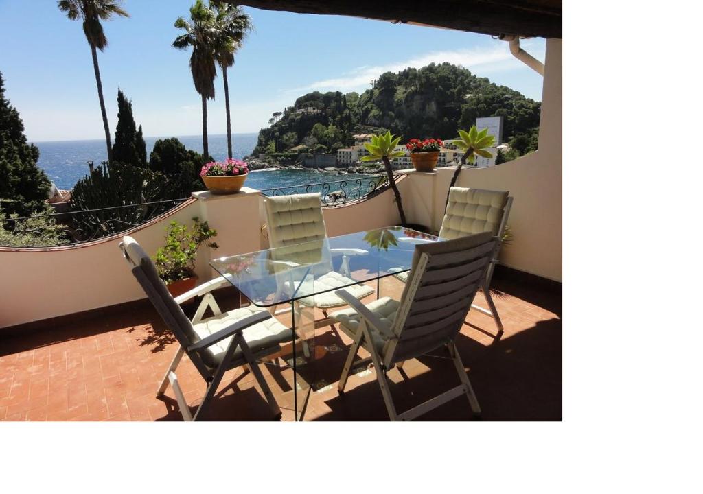 eine Terrasse mit einem Glastisch, Stühlen und Meerblick in der Unterkunft La Bomboniera della Brigata Spendereccia! in Taormina