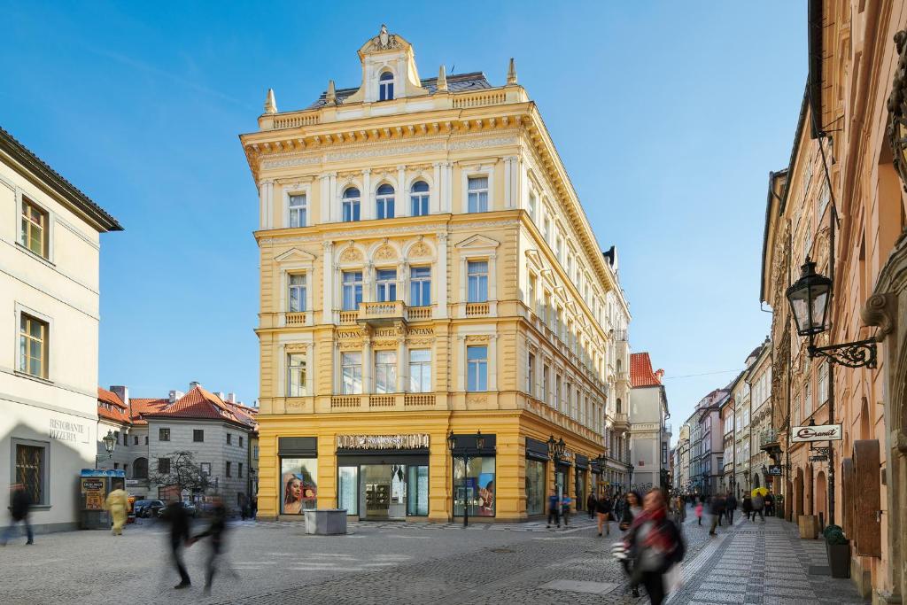 ein großes gelbes Gebäude in einer Stadtstraße in der Unterkunft Ventana Hotel Prague in Prag