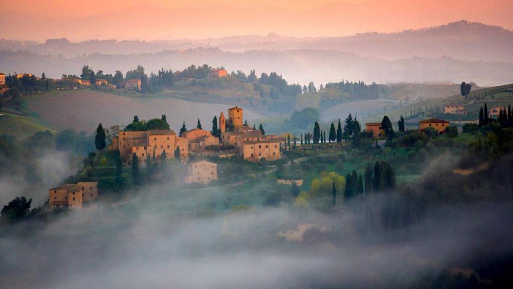 a town on a hill in the fog with buildings at Hapimag Resort Tonda in Montaione