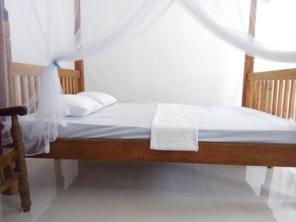 a bedroom with a bed with white sheets and a window at T & U Homestay in Katunayaka