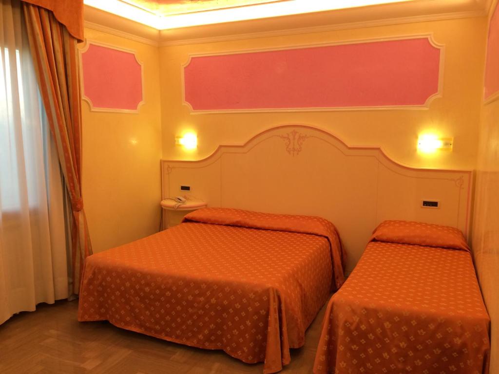 Campagna LupiaにあるLocanda Zabottoのオレンジのシーツが備わる客室内のベッド2台