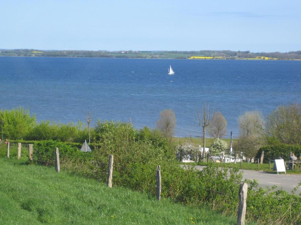 un velero en el agua con una carretera y una valla en Ferienwohnung Haffblick, en Westerholz