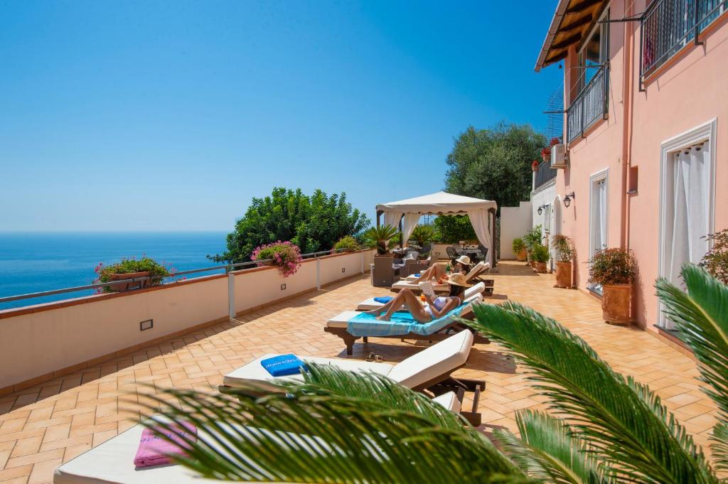 two people sitting on a balcony with the ocean in the background at Villamena in Furore