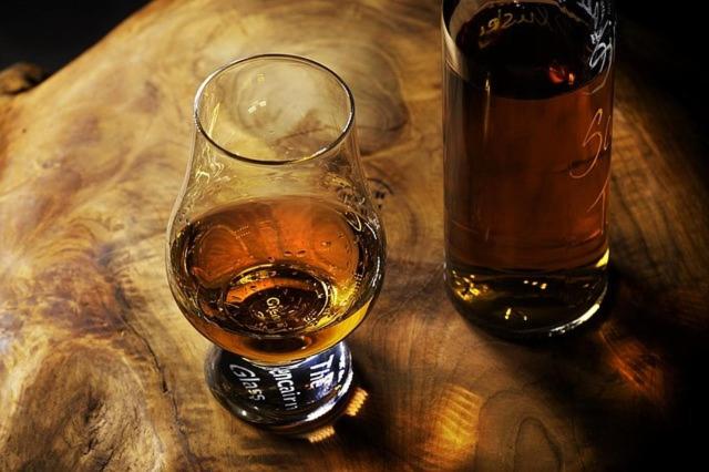 una copa de whisky junto a una botella en una mesa en Kindale House, en Helmsdale