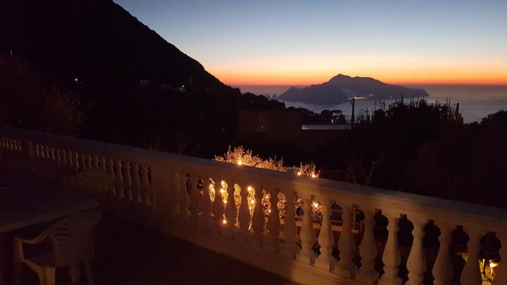 a sunset behind a fence with a mountain in the background at Il Profumo di Capri in Massa Lubrense
