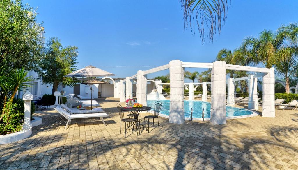 un patio con mesa y sillas junto a una piscina en Hotel Nicolaj, en Polignano a Mare