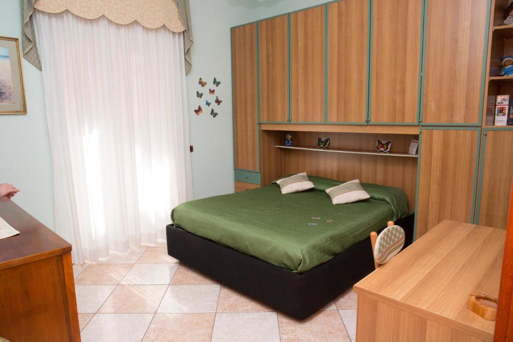 a bedroom with a bed with green sheets and a window at BUTTERFLY in Castellammare di Stabia