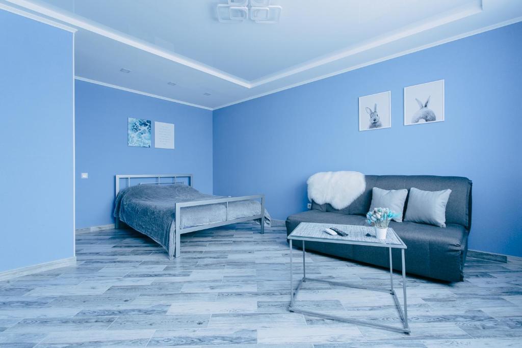 ein blaues Wohnzimmer mit einem Sofa und einem Bett in der Unterkunft Сучасна 1-кімнатна квартира in Winnyzja