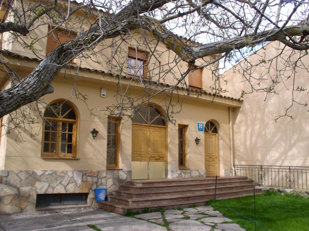 uma casa com portas castanhas e uma árvore em La Noguera em Palomera