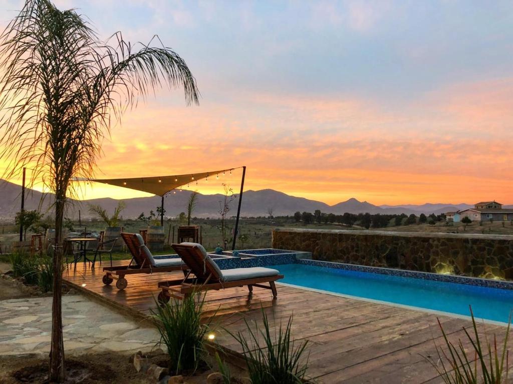 a villa with a swimming pool at sunset at Luna Del Valle in Valle de Guadalupe