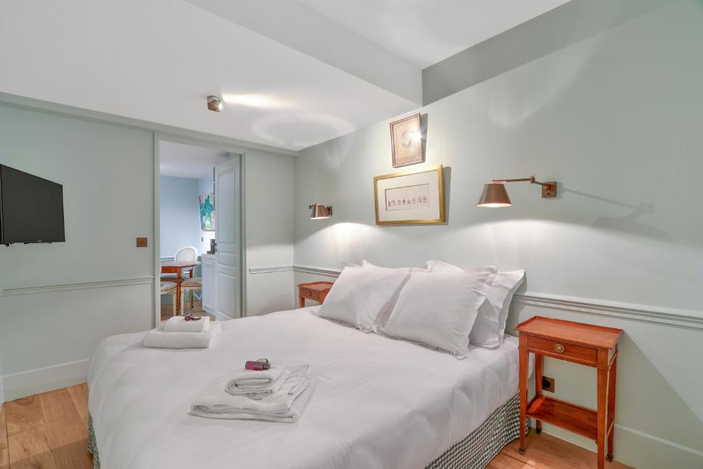 een slaapkamer met een bed met witte lakens en een televisie bij Pick A Flat's Apartments in Saint Germain - Paul-Louis Courier in Parijs