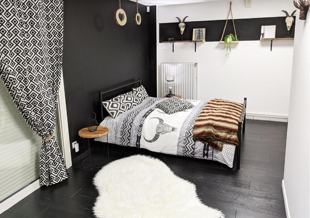 a black and white bedroom with a bed and a rug at Dépendance chaleureuse dans le vignoble nantais in La Haie-Fouassière