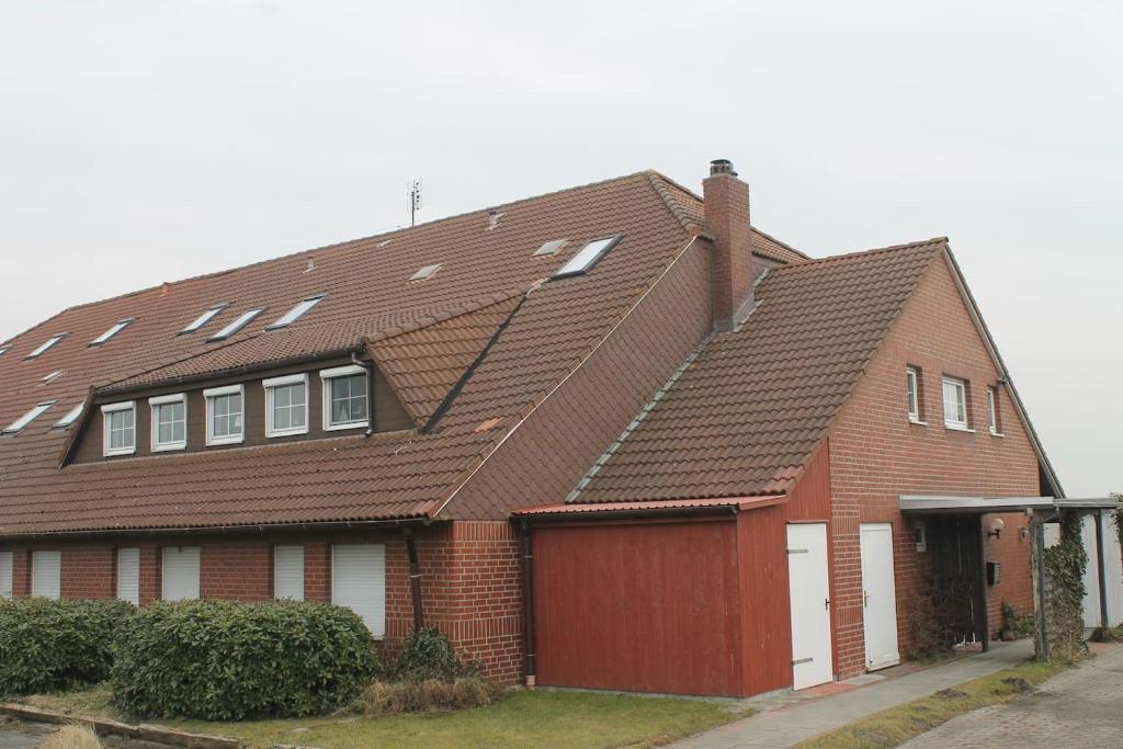 Schweiburg的住宿－Deichstube，一间棕色砖屋,设有红色车库