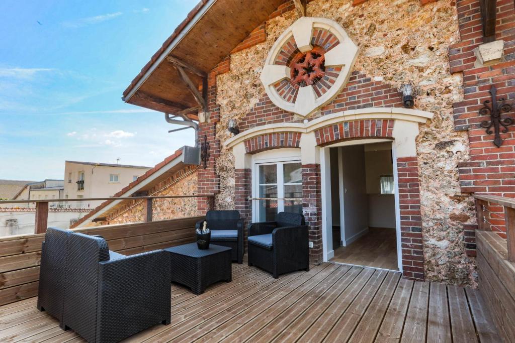 eine Terrasse mit Stühlen und eine Uhr in einem Backsteingebäude in der Unterkunft Gîte Le Pressoir in Vinay