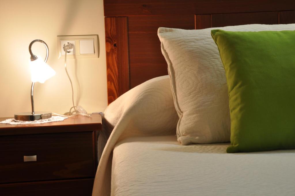 a bed with a green pillow and a lamp on a nightstand at Hostal Rural Letur in Letur