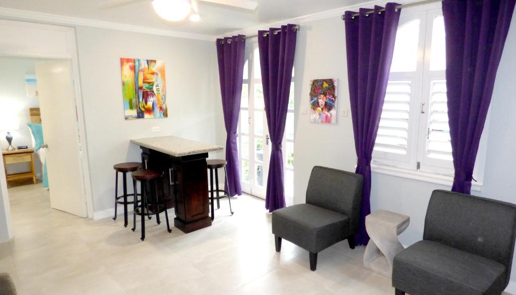 a living room with purple curtains and a piano at Beach One Bedroom Suite A17 in Ocho Rios