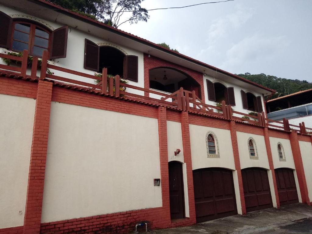 um edifício vermelho e branco com portas e janelas em hostel MdeMarilia em Nova Friburgo