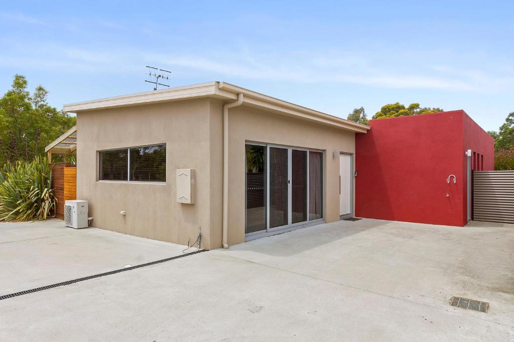 a small house with a red wall at 170 Hazards View Drive - Unit 2 in Coles Bay