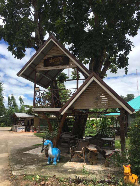 un dinosaurio de juguete parado frente a un árbol en ฟอเรสท์, en Roi Et