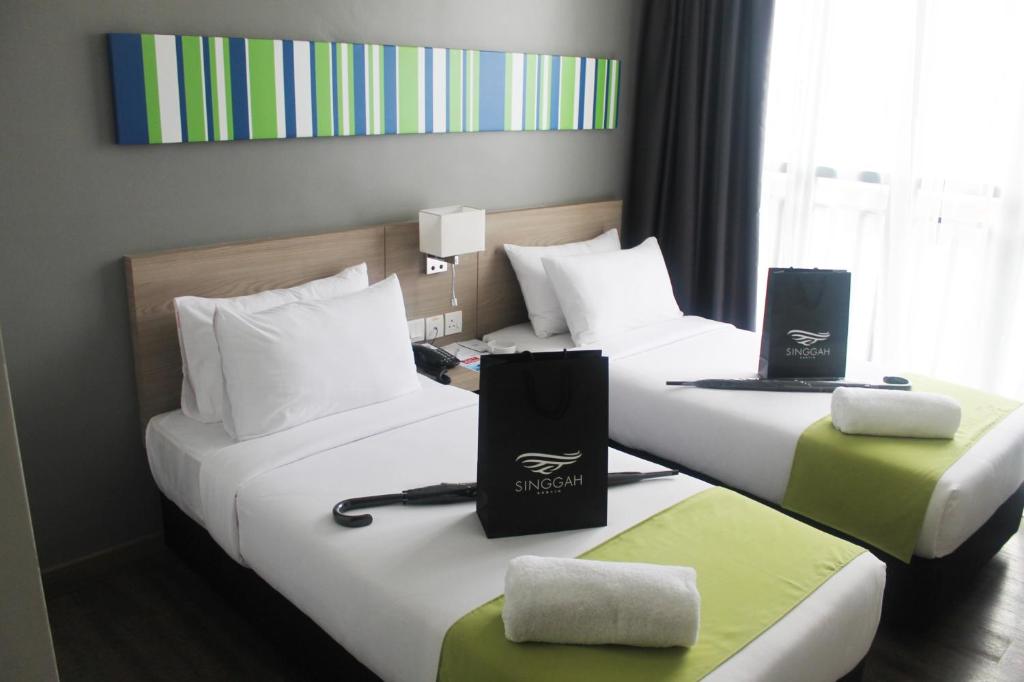 2 lits dans une chambre d'hôtel avec des sacs dessus dans l'établissement Singgah Kertih, à Kerteh