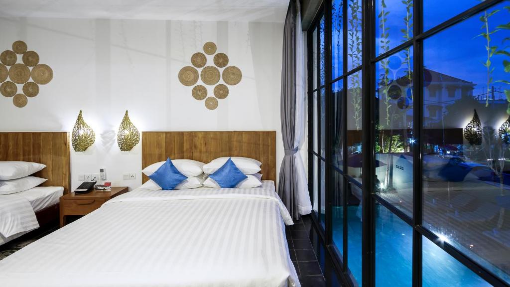 a bedroom with a bed with blue and white pillows at Vihara The City of Temples in Siem Reap