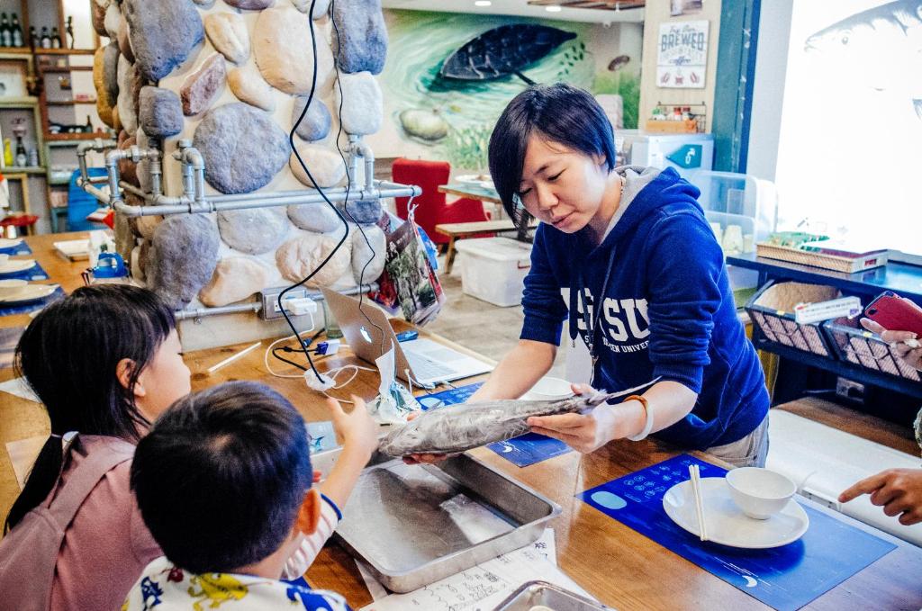 a woman teaching two children how to make a piece of wood at Hualien Wow Hostel in Hualien City