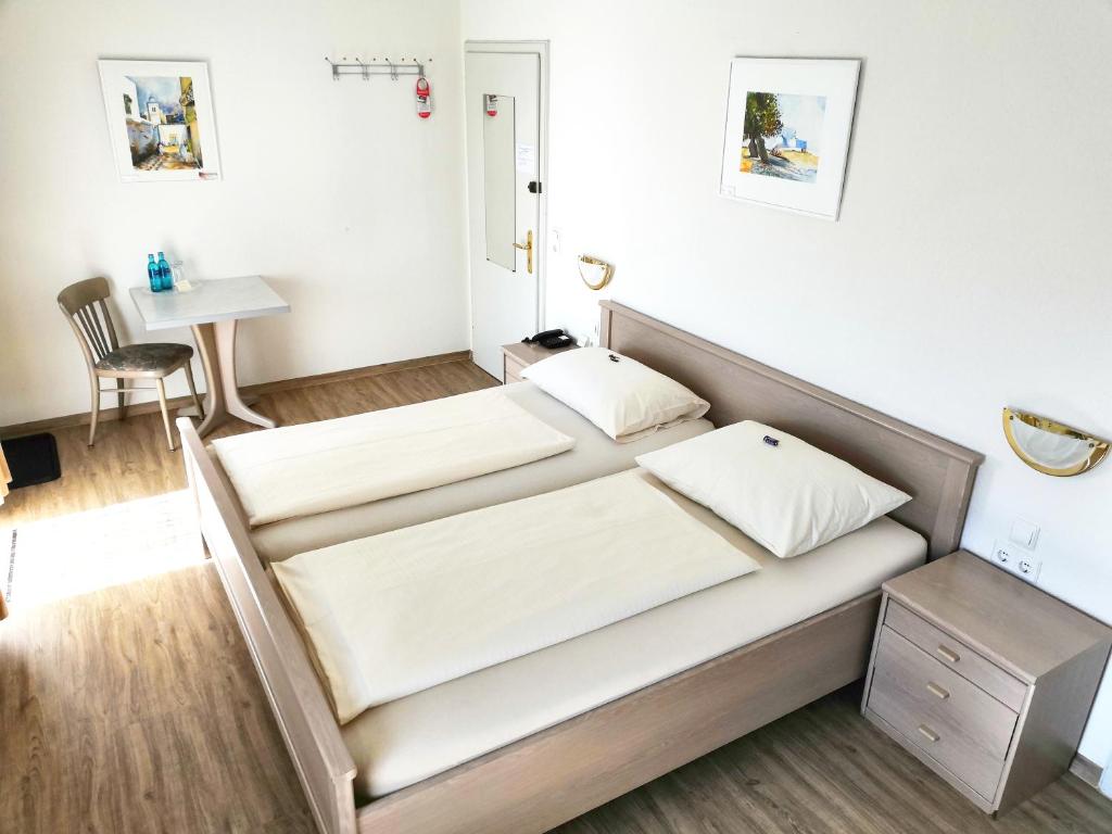 a bedroom with two beds and a table at Hotel Fantasie in Ansbach