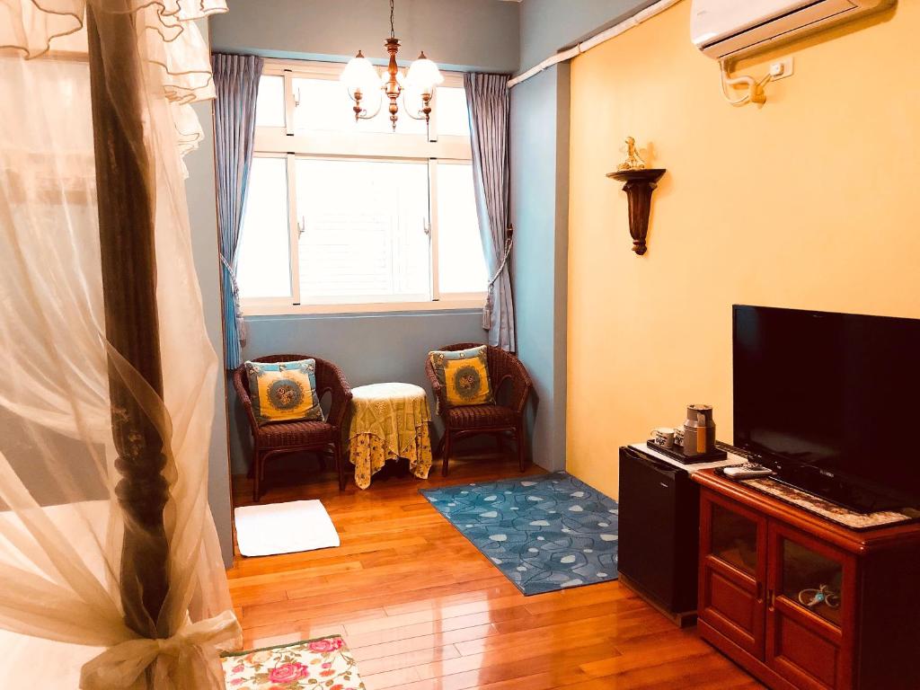 a living room with a tv and chairs and a window at Hope &amp; Sea Homestay in Hualien City