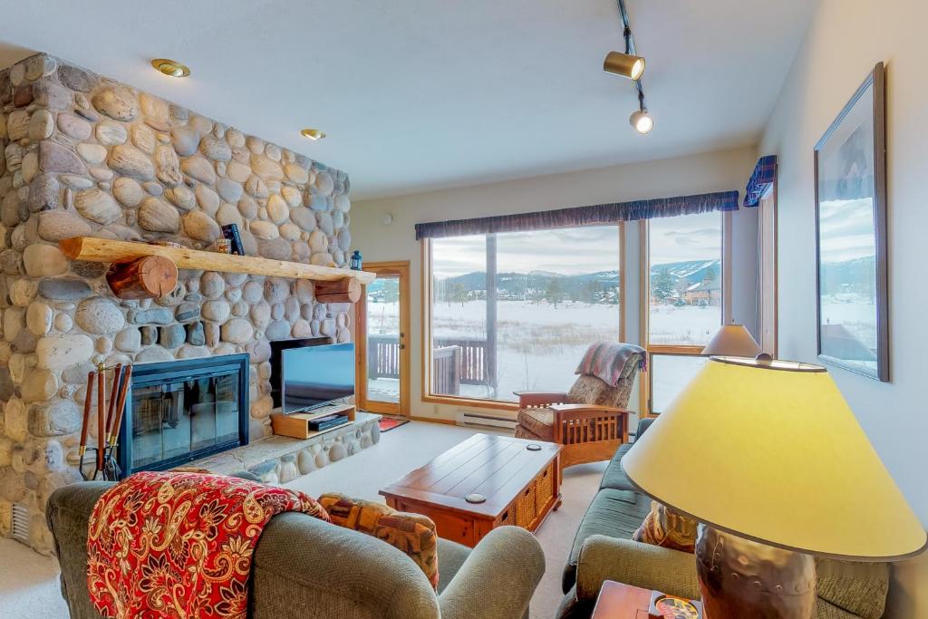 a living room with a fireplace and a stone wall at Park 282 in Big Sky