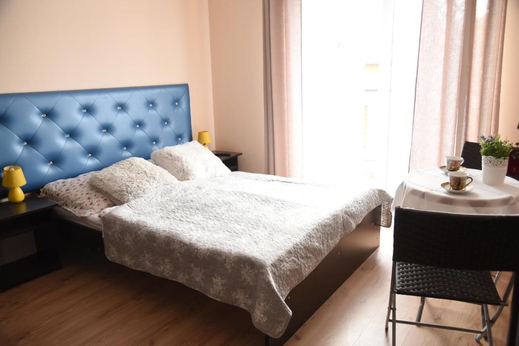 a bedroom with a bed with a blue headboard and a table at Nestor II in Mrzeżyno