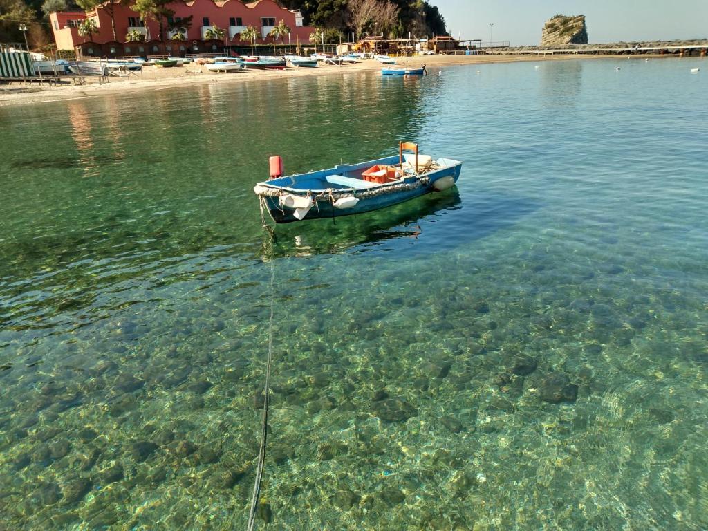 ein kleines Boot im Wasser in der Nähe eines Strandes in der Unterkunft Confort By The Sea in Vico Equense