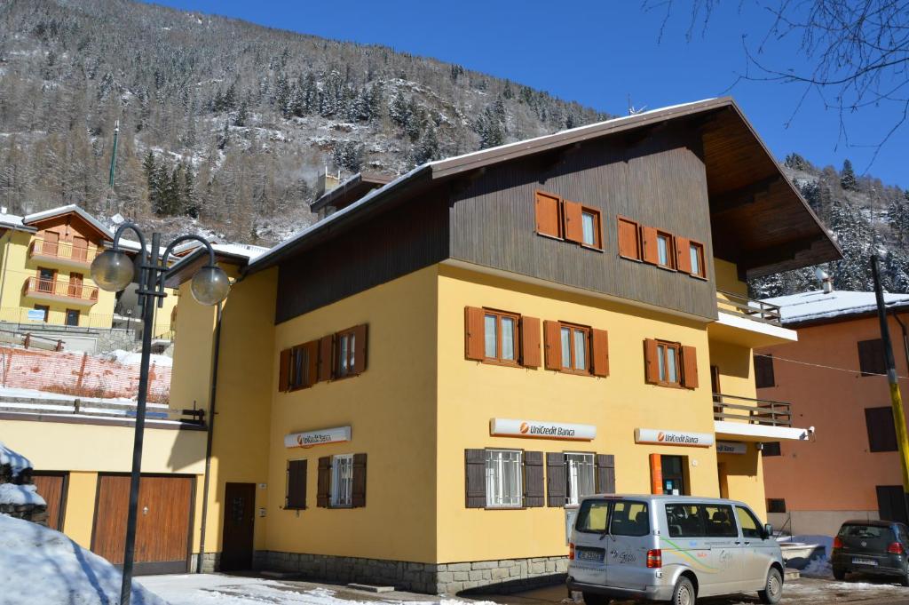 ein gelbes und schwarzes Gebäude mit einem Auto, das vorne parkt in der Unterkunft Casa Caritro in Ossana