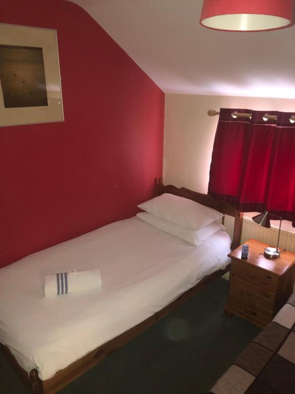a bedroom with a white bed with a red wall at Red Lion Accommodation in Abingdon