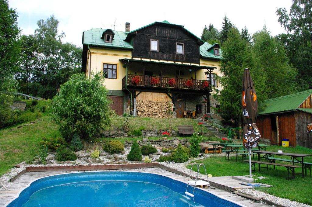 a house with a swimming pool in front of it at Penzion u Lebedů in Kašperské Hory