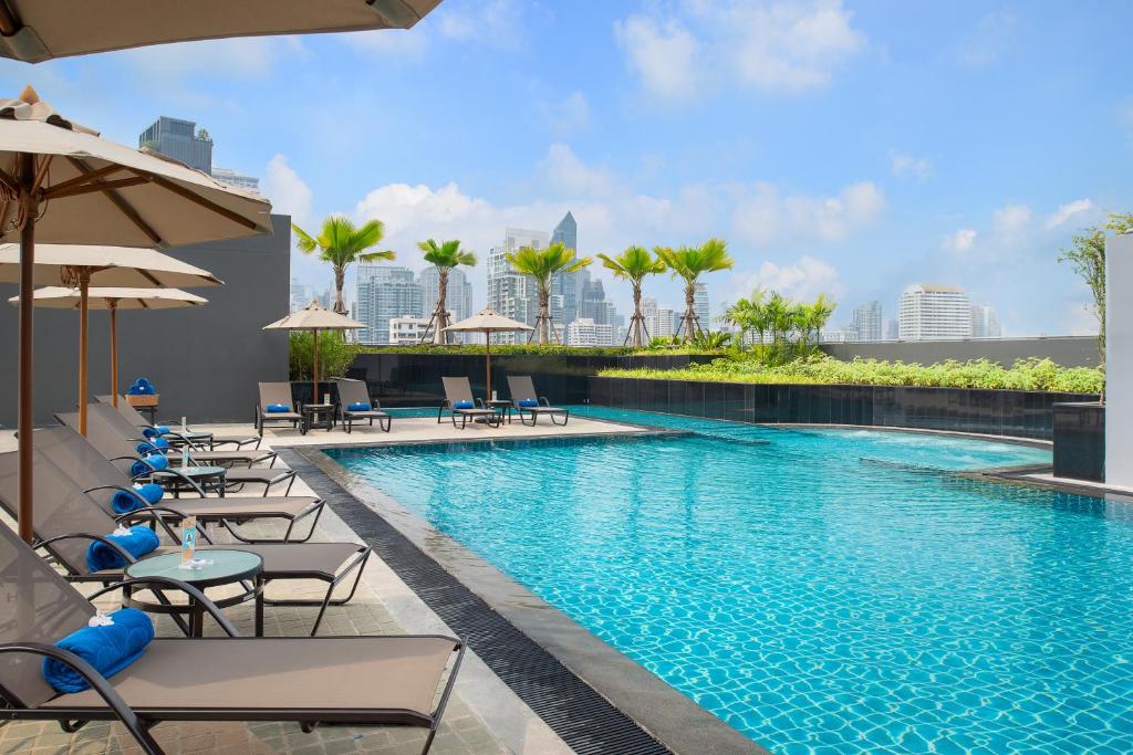 a swimming pool with chairs and umbrellas at Hotel Nikko Bangkok - SHA Extra Plus Certified in Bangkok